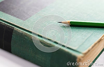 A green wooden pencil is placed on the hardback or textbook. selective focused Stock Photo