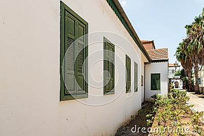 Green wooden vintage window shutters on old white painted houses on the side quiet street with stone pavement in Zikhron Yaakov Editorial Stock Photo