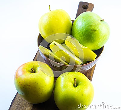 Green and yellow apples and slices in a violet cup on a wooden board on a white background Stock Photo