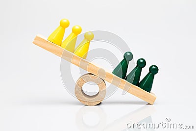 Green and yellow game pieces on a wooden seesaw Stock Photo