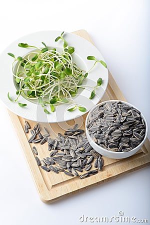 Green young sunflower sprouts on salad plate and sunflower seeds Stock Photo