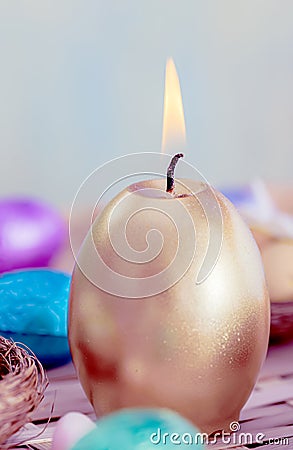 Greeting card Easter burning golden candle. Festive easter concept of candle and eggs on a wooden table. Stock Photo