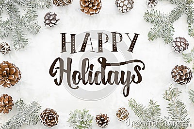 Greeting card happy holidays hand lettering on winter background with cones and fir branches. Flat lay. Stock Photo