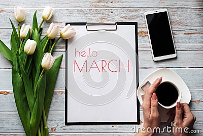 Greeting card with the inscription Hello March. Bouquet of white Tulip flowers with a Cup of coffee and a smartphone Stock Photo