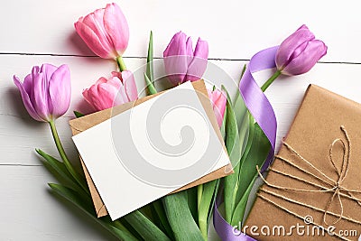 Greeting card mockup with gift box and tulip flowers bouquet with ribbon on white wooden background Stock Photo