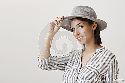 Greetings cowboy. Portrait of emotive woman in stylish striped blouse holding hat to salute or greet friend as if Stock Photo