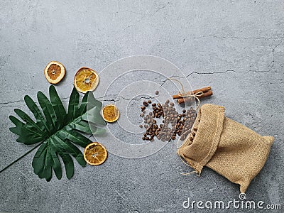 Grey background decorated with dried orange slices, cinnamon sticks and coffee bean in gunny sack Stock Photo