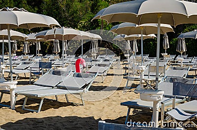 Grey beach umbrellas, chaise longues and inflatable pink flamingo. Stock Photo