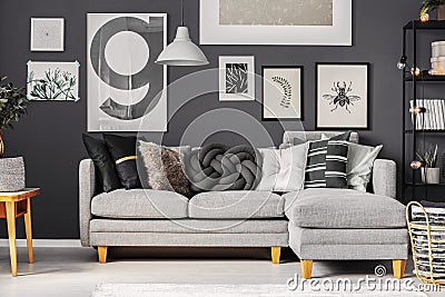 Grey and black pillows on comfortable corner sofa in scandinavian living room Stock Photo