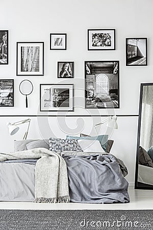 Carpet in front of bed and mirror in white and black bedroom interior with gallery. Real photo Stock Photo