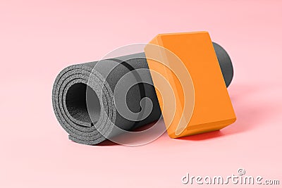 Grey exercise mat and yoga block on pink background Stock Photo