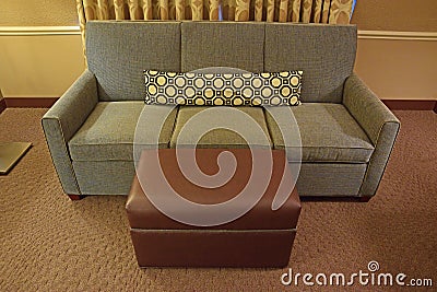 Grey Fabric Sofa with Brown Leather ottoman and long narrow pillow Stock Photo