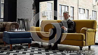 Grey hair caucasian man watching laptop on sofa Stock Photo