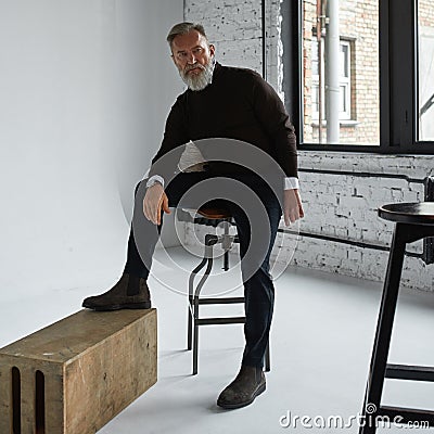 Grey hair serious man posing in spacious flat Stock Photo