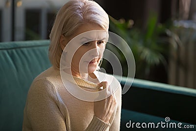 Grey haired mature woman in sweater suffering from high temperature Stock Photo