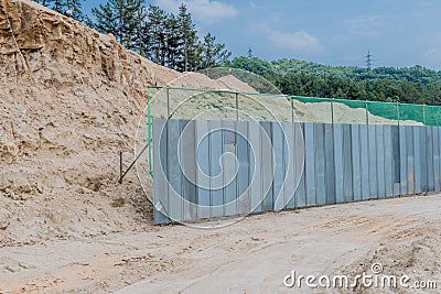 Grey metal fence beside dirt hill Stock Photo