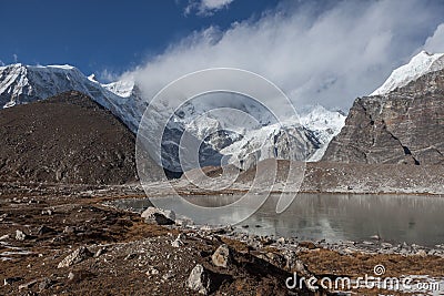 Grey moraine lake and snowy mountain peak covered. Stock Photo