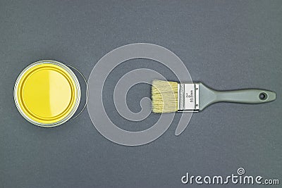 Grey paintbrush with natural bristle and can of yellow paint for house renovation works Stock Photo