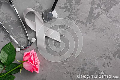 Grey ribbon, stethoscope and pink rose on a concrete background. Parkinson`s disease or brain cancer awareness concept Stock Photo