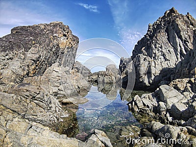 Grey rock formations and clear water rock pool on an ocean shore Stock Photo