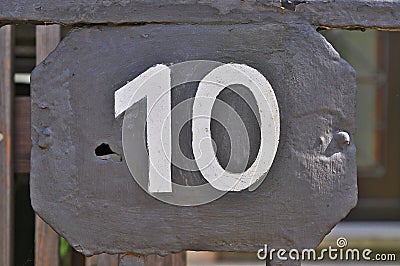 A grey house number plaque, showing the number ten Stock Photo