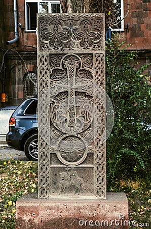 Grey cross-stone with an arch over the cross, a carved figure of a Saint on a horse and a circle-a symbol of eternity on the Alley Stock Photo