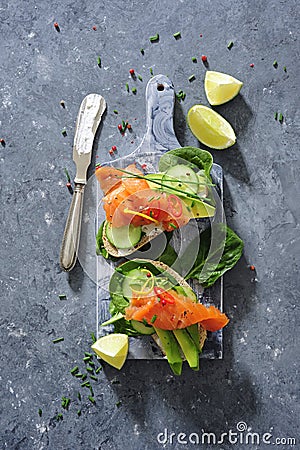 Whole grain bread sandwiches with fresh cucumber, spinach leaves, avocado and smoked salmon Stock Photo