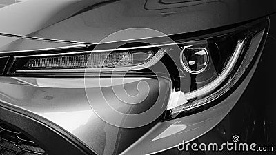 Greyscale closeup of a grey modern car headlight under the lights Stock Photo