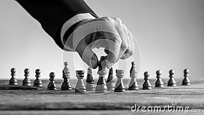 Greyscale image of a male hand reaching dark queen chess piece Stock Photo