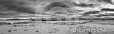 Greyscale panoramic shot of the dark clouds covering the beach Stock Photo