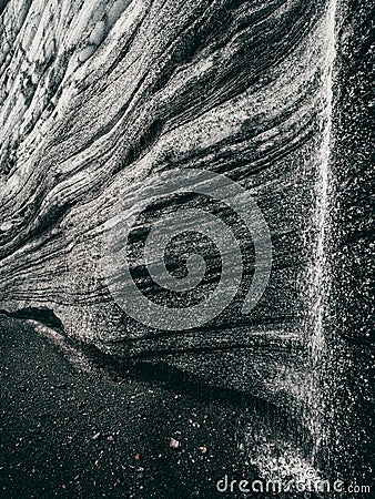 Greyscale of a rock formation with a small stream trickling down, Katla region of Iceland Stock Photo