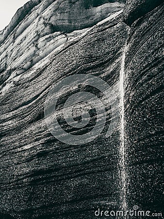 Greyscale of a rock formation with a small stream trickling down, Katla region of Iceland Stock Photo