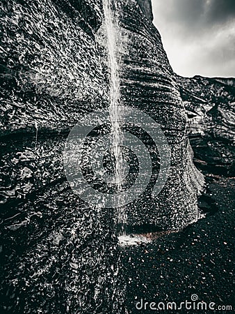 Greyscale of a rock formation with a small stream trickling down, Katla region of Iceland Stock Photo