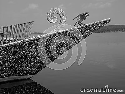 Greyscale shot of a boat with the statue of a bird on it captured on a sunny day Stock Photo
