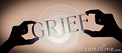 Grief - human hands holding black silhouette word Stock Photo