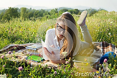 Gril lying on grass and writing on notebook Stock Photo