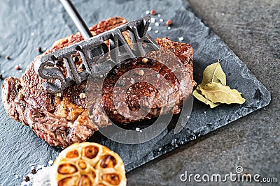 Grilled beef steak fillet with ingredients like sea salt, pepper, onion and metal letters on black board, food background for rest Stock Photo