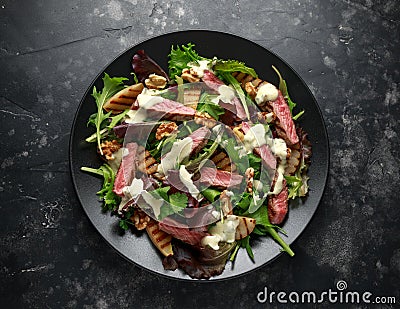 Grilled Beef Steak salad with pears, walnuts and greens vegetables and blue cheese sauce. healthy food. Stock Photo