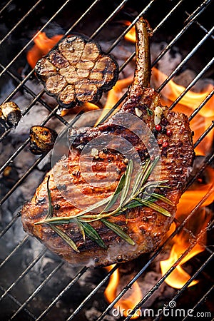 Grilled bone-in pork chop, pork steak, tomahawk in a rosemary-garlic marinade on a flaming grill Stock Photo