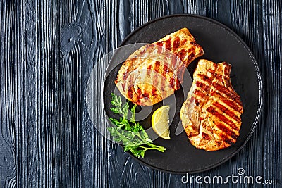 Grilled bone-in pork chops on a black plate Stock Photo