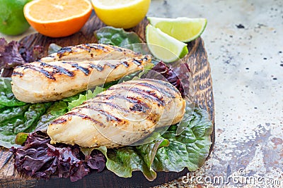 Grilled chicken breast in citrus marinade on salad leaves and wooden board, horizontal, copy space Stock Photo