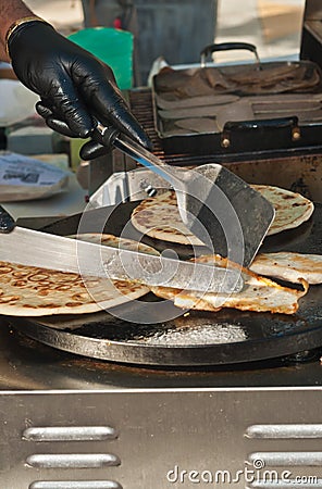 Grilled chicken and flat bread in a flat grill, being moved by a vender with knife and spatula Stock Photo