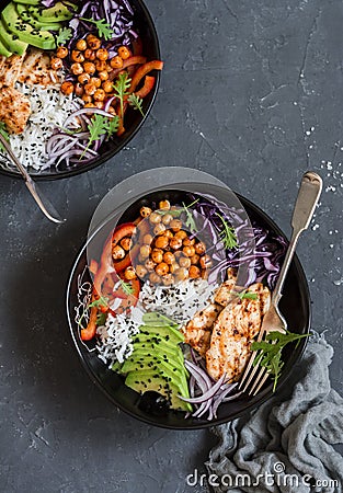 Grilled chicken, rice, spicy chickpeas, avocado, cabbage, pepper buddha bowl on dark background, top view. Stock Photo