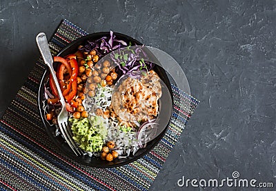 Grilled chicken, rice, spicy chickpeas, avocado mash, cabbage, pepper buddha bowl on dark background, top view. Delicious balanced Stock Photo