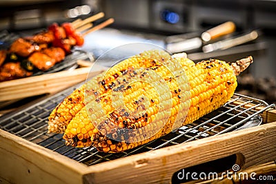 Grilled corn on the grill with blur BBQ beside. Stock Photo