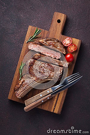 Grilled cowboy beef steak, herbs and spices on a dark stone background. Top view Stock Photo