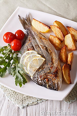 Grilled dorado fish with fried potatoes and tomato close-up Stock Photo