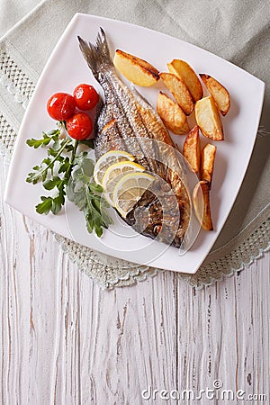 Grilled dorado fish with fried potatoes and tomato. Vertical top Stock Photo