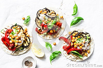 Grilled eggplant, sweet peppers, cauliflower and spicy chickpeas vegetarian tortillas on a light background, top view. Healthy foo Stock Photo