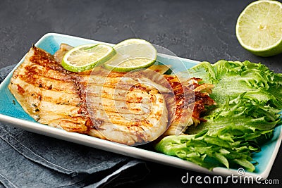 Grilled fish with fresh herbs and lime in a rectangular blue plate. Stock Photo